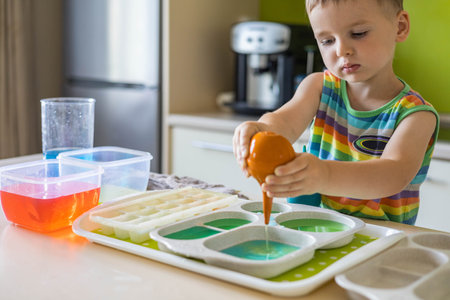 Cute baby boy learning mixing different colors with water and paint in containers. Early developmentの写真素材