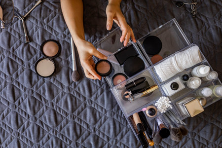 Woman hands tidying up putting powder container into acrylic storage box makeup products placementの写真素材