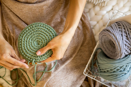 Closeup female hands knitting interior decor basket use green ribbon yarn and crochet needle