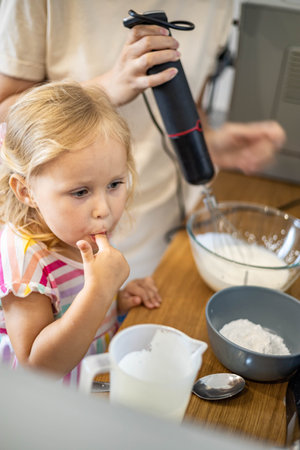 Caring mother cooking with daughter and son together family preparing waffles mixing dough