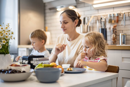 Happy family cooking baking waffles together enjoying weekend breakfast at kitchen homeの写真素材