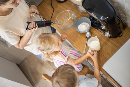 Caring mother cooking with daughter and son together family preparing waffles mixing doughの写真素材
