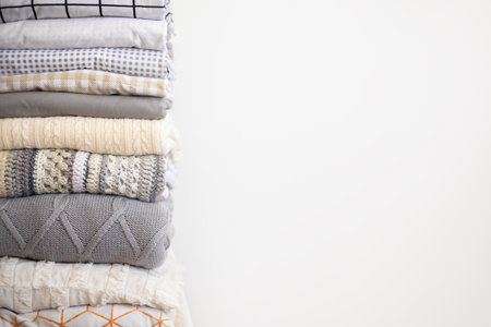 Stack bed linens and knitted warm plaids domestic soft textile with copy space isolated on whiteの写真素材