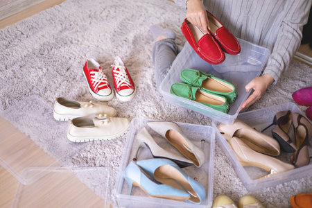 Female hands pack shoes on heels into plastic box home wardrobe storage method organization top viewの写真素材