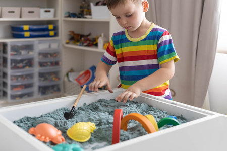 Overjoyed male kid playing kinetic sand early development education game fine motor skillsの写真素材