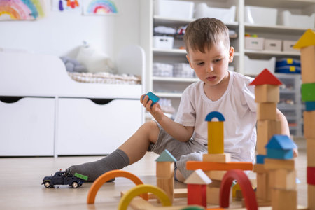 Confident male kid building fortress tower architecture wooden bricks ecology Montessori materialの写真素材