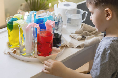 Cute baby boy learning mixing different colors with water and paint in containers. Early developmentの写真素材