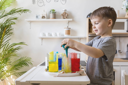 Cute baby boy learning mixing different colors with water and paint in containers. Early developmentの写真素材