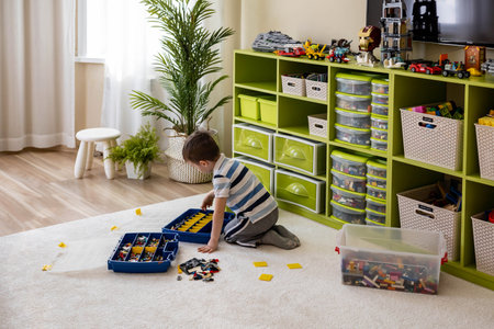 Khabarovsk, Russia, February 18, 2022. Boy sorting Lego boxes with cells. Childrens room cleanupのeditorial素材