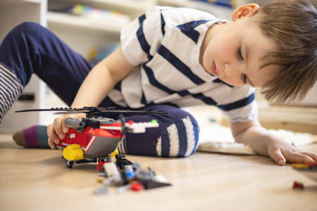 Khabarovsk, Russia, June 4, 2022. Cute baby boy constructing helicopter Lego pieces at childish roomのeditorial素材