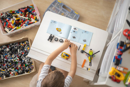 Khabarovsk, Russia, August 07, 2022. Male kid constructing according to instructions toy excavator and use Lego Classicのeditorial素材