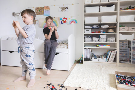 Khabarovsk, Russia, June 4, 2022. Two male kid playing Lego pieces on floor at childish roomのeditorial素材