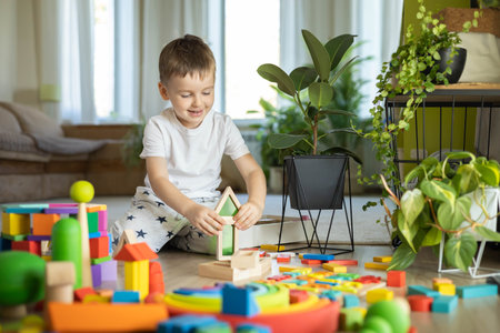 Confident male kid building fortress tower architecture and forest with trees wooden bricks ecology Montessori materialの写真素材