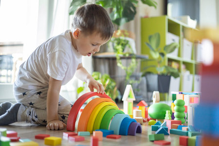 Funny baby boy playing multicolored arch Montessori wooden material structure building closeupの写真素材