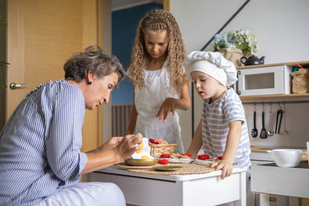 Mother and cute baby boy and girl cooking food at childish kitchen playing chef educational...