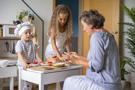 Mother and cute baby boy and girl cooking food at childish kitchen playing chef educational...