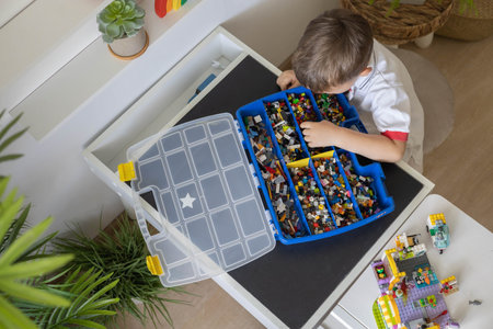 Khabarovsk, Russia, August 02, 2022. Cut child male sorting heap of small Lego pieces into boxesのeditorial素材