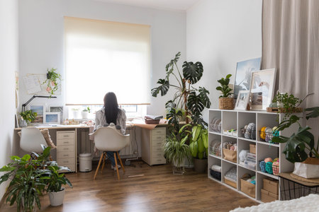 Smiling woman skilled tailor clothes manufacture process on sewing machine posing at workplaceの写真素材