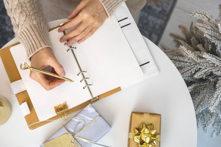 Happy young woman writing wish list dream notes for Christmas holidayの写真素材
