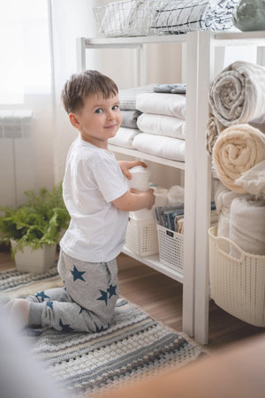 The child puts the bedding in a closet with neatly folded things. vertical storage.の写真素材