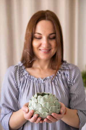 A young pretty woman housewife holds a candlestick with a burning candle in her hands.の写真素材