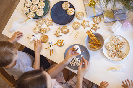 Topview female hands hold a mug with hot chocolate and a marshmallow snowman. Christmas gingerbread, garlands and fir branches.の写真素材