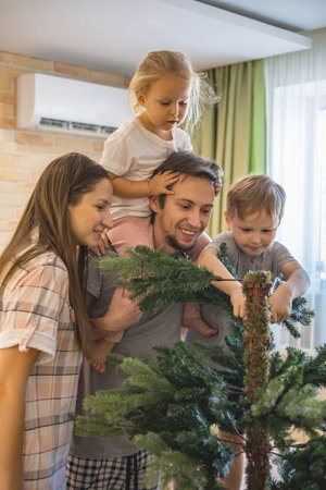 Family assembling, shaping hook-in artificial Christmas Tree at home