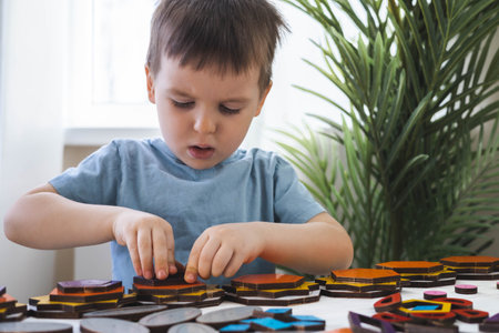 Attentive cute baby boy learning geometric figure shapes playing multicolored wooden constructionの写真素材