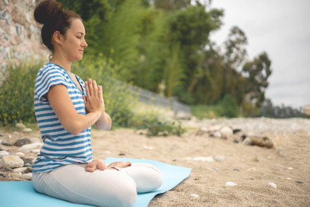 Concentrated woman sitting in lotus position yoga at summer