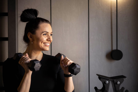 Portrait happy athletic brunette woman posing at mirror holding dumbbells smiling healthy lifestyle
