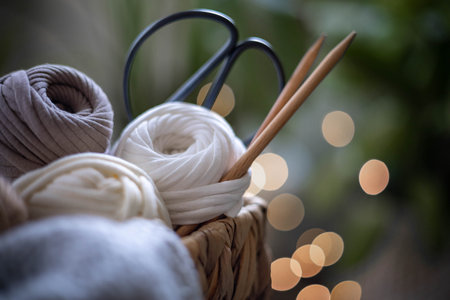 Cozy homely atmosphere. Female hobby knitting. Yarn in neutral shades in a basket woven from natural...
