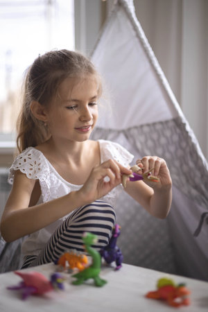 Happy curly blonde little girl sculpt dinosaurs from plasticine enjoy childhoodの写真素材