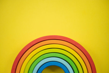 Wooden multicolored rainbow Montessori material for kids early development isolated on yellowの写真素材