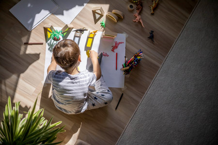Male kid playing wooden bricks and dinosaurs drawing shadow on paper early development educationの写真素材