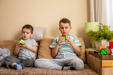 Khabarovsk, Russia, February 18, 2022. Two male kids brothers assembling Rubiks cube thinking solving logic decisionのeditorial素材