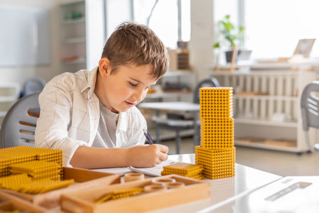Smiling male kid with Montessori math golden bank material beads alternative counting developmentの写真素材