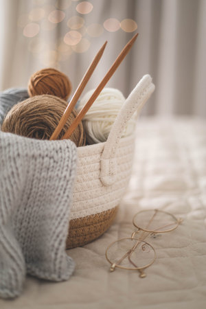 Cozy homely atmosphere. Female hobby knitting. Yarn in neutral shades in a soft basket of white and brown cord.の写真素材