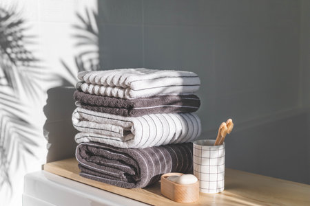 Bath spa soap towels pile soft textile cotton washcloth on wooden tabletop at sunny bathroom blurred backgroundの写真素材