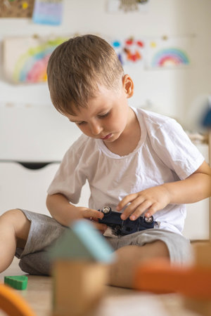 Concentrated male kid playing with car automobile at childish room Montessori eco friendly materialの写真素材