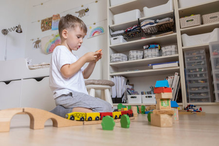 Preschool baby boy playing wooden Montessori materials rainbow arch railways at childish roomの写真素材