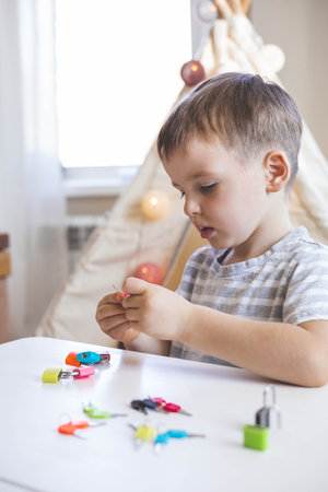 The child works with Montessori material with colored locks. Picks up keys. Develops fine motor skills.の写真素材