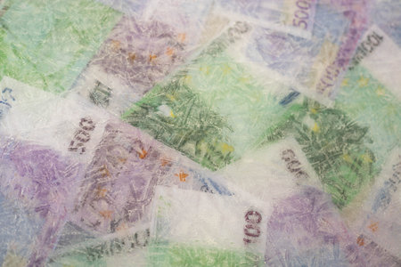 Blurred photo of one hundred and five hundred euros are defrosted in ice. The European cash currency is frozen.の写真素材