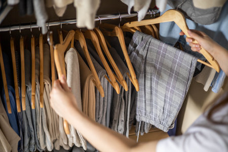 A woman chooses her trousers in the wardrobe. The concept of a harmonious capsule wardrobe.の写真素材