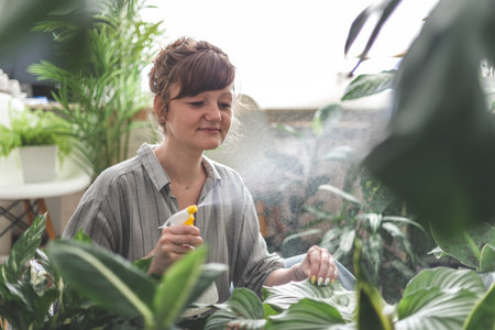 A young woman enjoys caring for flowers. Watering indoor plants and admiring them.の写真素材
