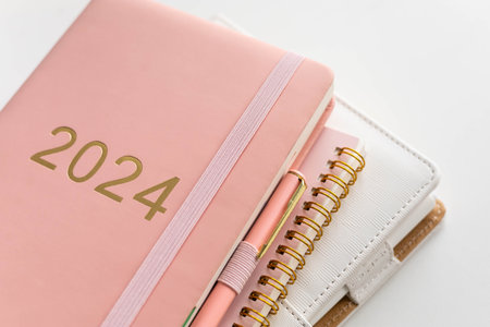 Pink coral colored diary for the year 2024 and many other diaries, pen, white backgroundの写真素材