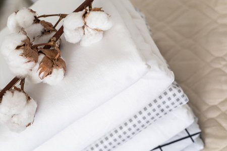 Cotton branch with pile of folded bed sheets and blankets