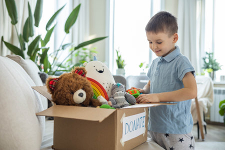 Boy child puts toys in a cardboard box for charity. Donation concept.の写真素材