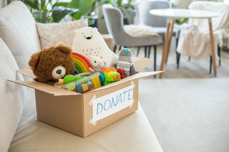 On the living room couch is a box full of toys for donation.の写真素材