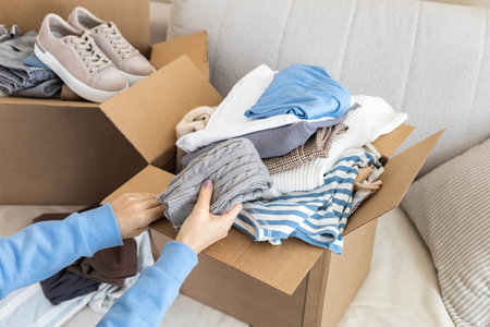 Donation concept. A woman puts clothes in a box at home for donation, recycling or disposal.の写真素材