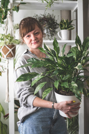 A young woman enjoys caring for flowers. Watering indoor plants and admiring them.の写真素材